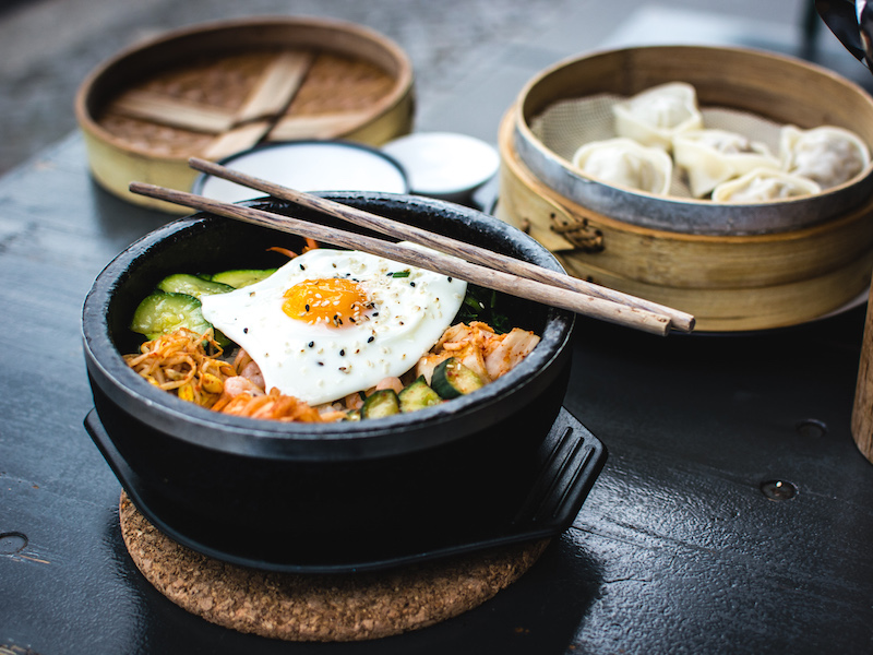 Ramen bowl topped with vegetables and sunny-side-up egg. 