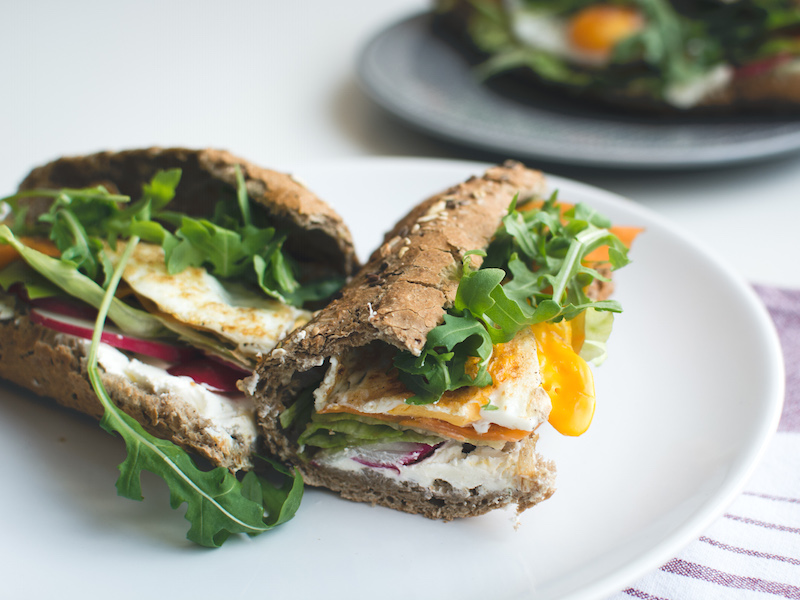 Healthy morning style whole grain baguette filled with egg, cheese and fresh vegetables.